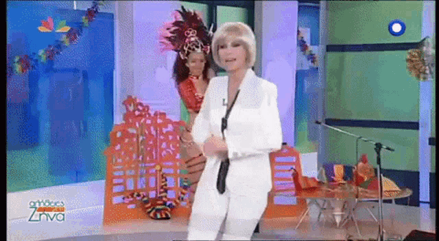 a woman in a white suit stands in front of a microphone in front of a sign that says zhiva