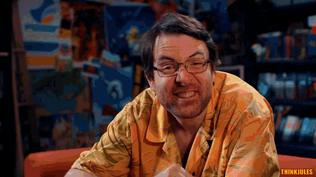 a man wearing glasses and a yellow shirt with think jules written on the bottom right