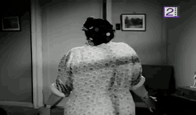 a woman is standing in a room with her arms outstretched and a picture on the wall .
