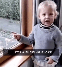 a baby is standing in front of a window with the words `` it 's a fucking bloke '' on the bottom .