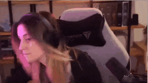 a woman is sitting in a chair wearing headphones and a pillow .