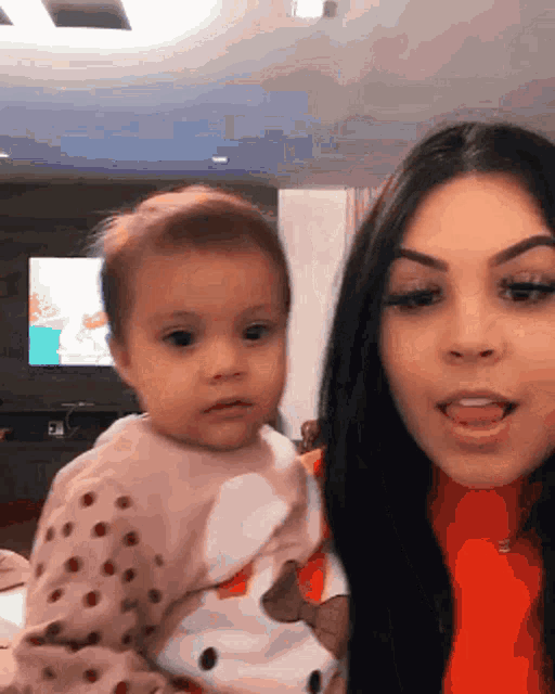 a woman is holding a baby in her arms in front of a television