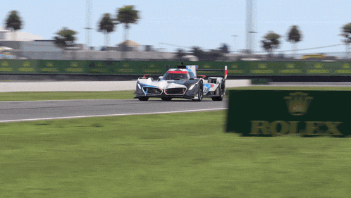 a race car on a track with a rolex sign in the foreground