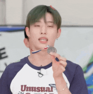 a young man wearing a shirt that says ' unusual ' on it is holding a medal