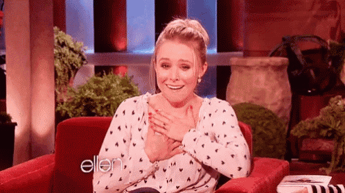 a woman is sitting in a chair with her hands on her chest and a smile on her face .