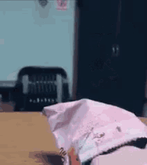 a person is sitting at a table with a piece of pink paper on it