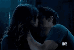 a man and a woman are kissing in a dark room with a mtv logo in the corner .