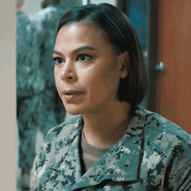 a woman in a military uniform has the letter t on her shirt