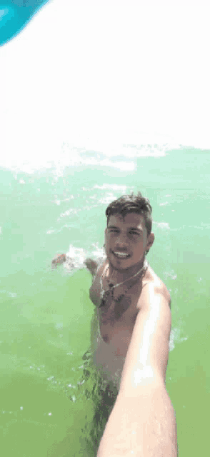 a shirtless man is swimming in the ocean and smiling