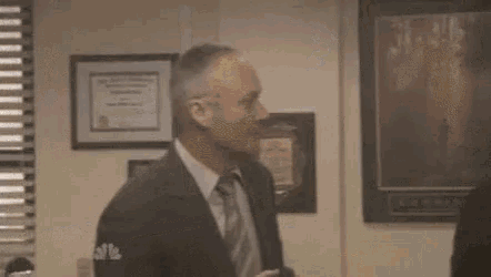 a man in a suit and tie is standing in front of a woman in a room .