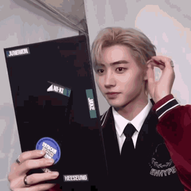a young man in a suit and tie has stickers on his jacket that say junewon and heeseung