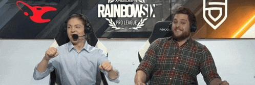 two men are sitting in front of a rainbows pro league banner