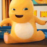 a yellow stuffed animal is sitting on a wooden table and smiling .