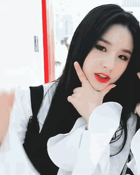 a woman with long black hair is making a funny face with her hand on her chin