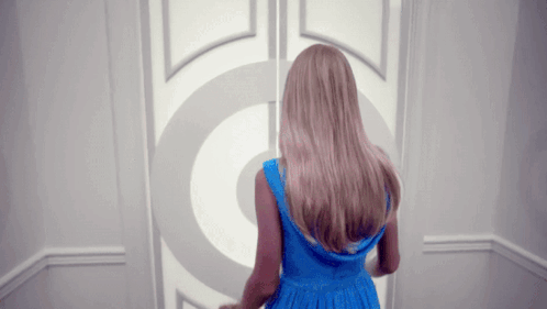 a woman in a blue dress is standing in front of a door that has the letter g on it