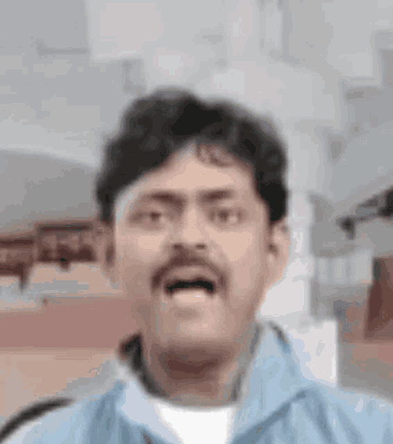 a man with a mustache is making a funny face and looking at the camera .