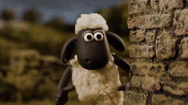 a cartoon sheep with big eyes is standing next to a brick wall