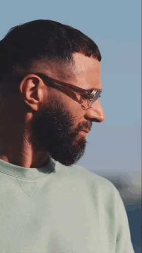 a man with glasses and a beard is wearing a green sweatshirt