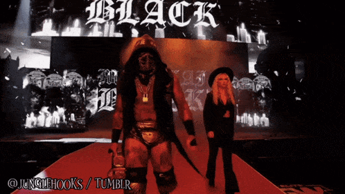 a man in a mask is walking on a red carpet in front of a black sign