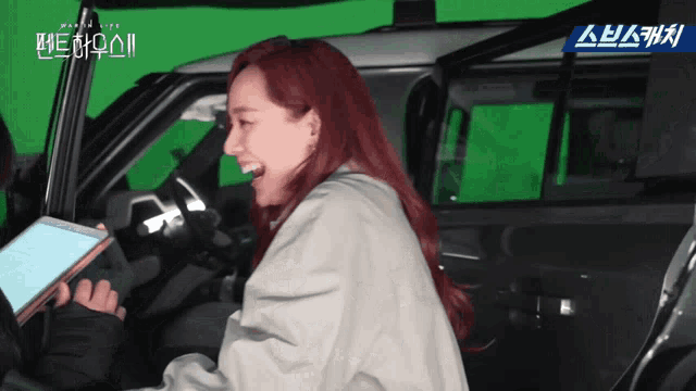 a woman with red hair is laughing in a car with a green screen
