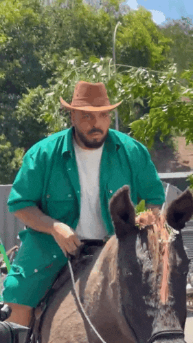 a man wearing a cowboy hat is riding a horse