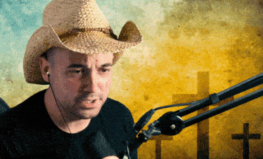 a man wearing a cowboy hat is talking into a microphone with a cross in the background