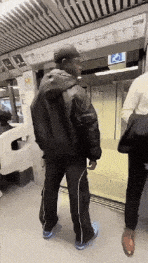 a man in a black jacket and black pants is standing on a train