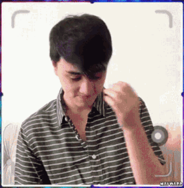 a man in a green and white striped shirt is taking a picture