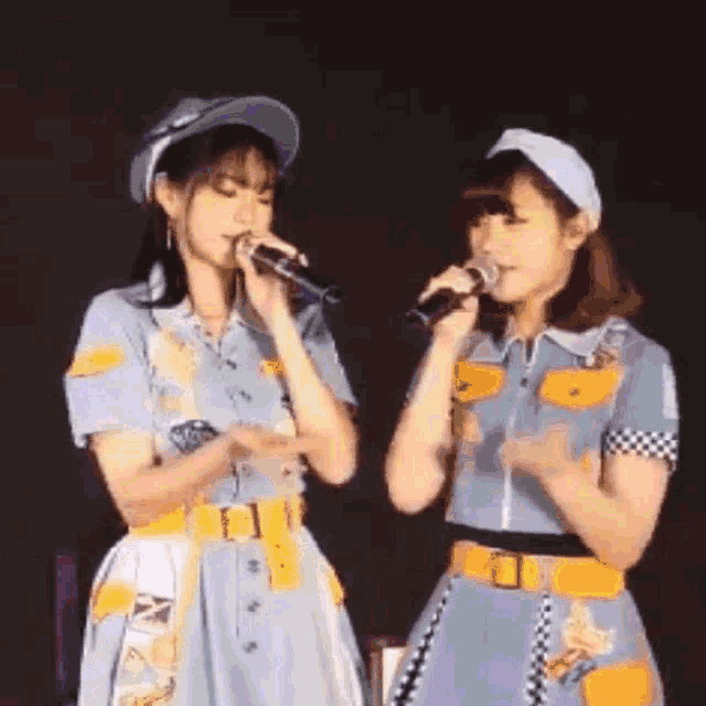 two women are singing into microphones on stage .
