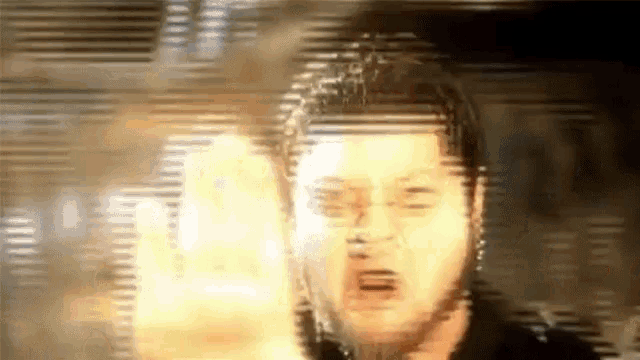 a blurry picture of a man 's face with a fire coming out of his eyes .