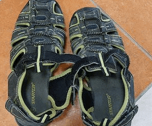 a pair of black and green sandals are sitting on top of a tiled floor .