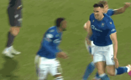 a group of soccer players in blue and white uniforms are running on the field .