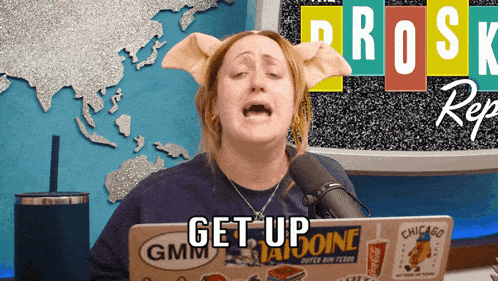 a woman with pig ears is sitting at a desk with a laptop that says get up