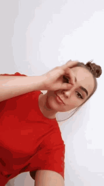 a woman in a red shirt is taking a selfie