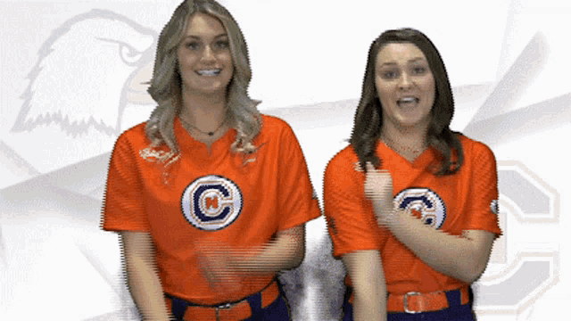 two women wearing orange shirts with a letter c on them