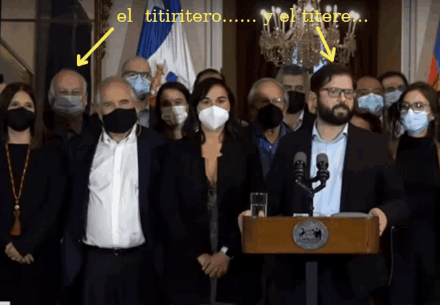 a group of people wearing face masks are standing in front of a podium with the words el titintero written above them