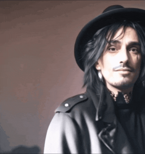 a man with long hair wearing a hat and a black coat