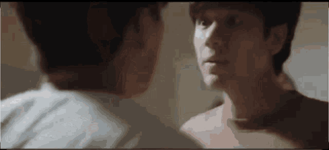two men are standing next to each other and looking at each other in a mirror .