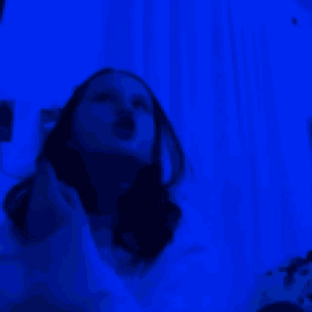 a girl is looking up in a blue light