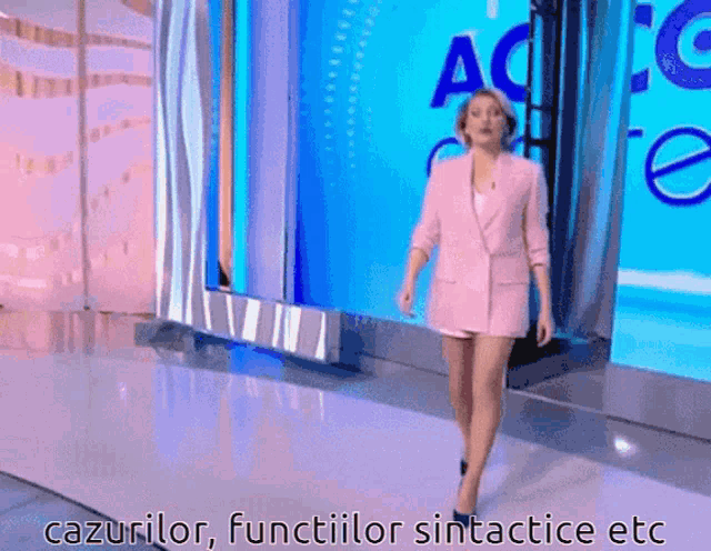 a woman in a pink suit is walking on a stage with the words cazurilor functionilor sintactice etc written below her