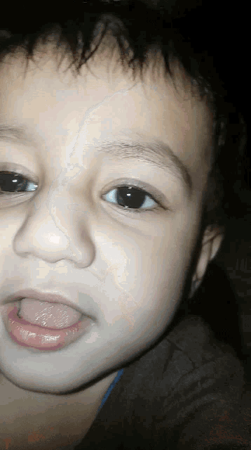 a young boy with his tongue out looks at the camera