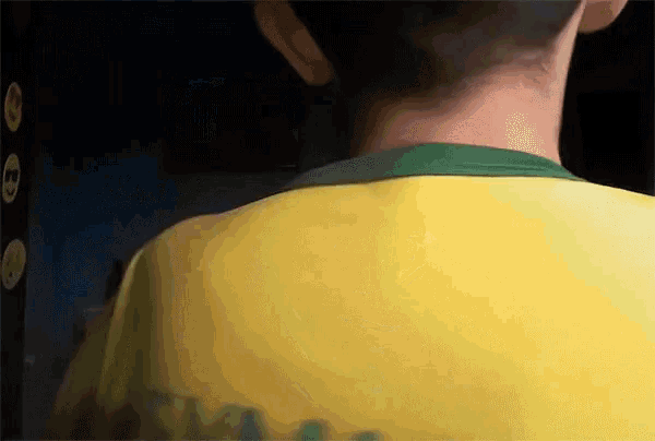 a person wearing a yellow shirt with a green collar has a tattoo on the back of their neck
