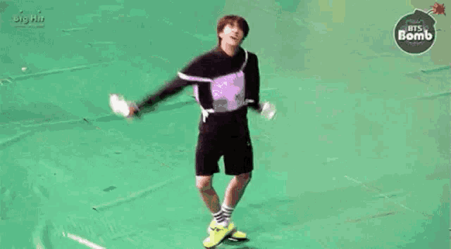a person is standing on a green surface with their arms outstretched and a backpack on .