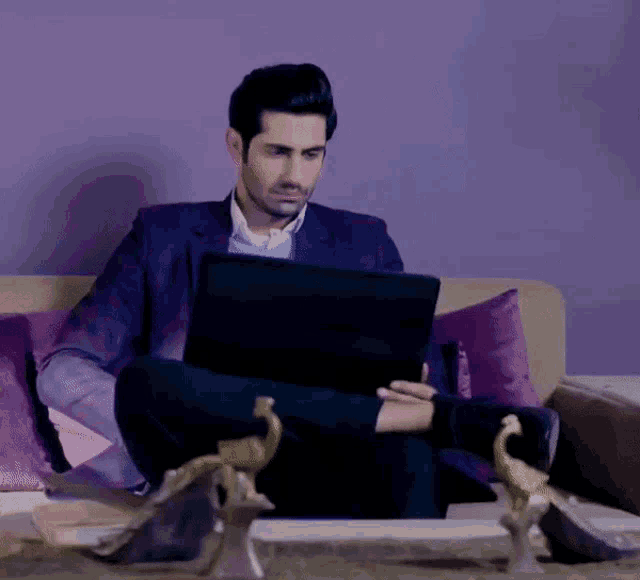 a man sitting on a couch using a laptop