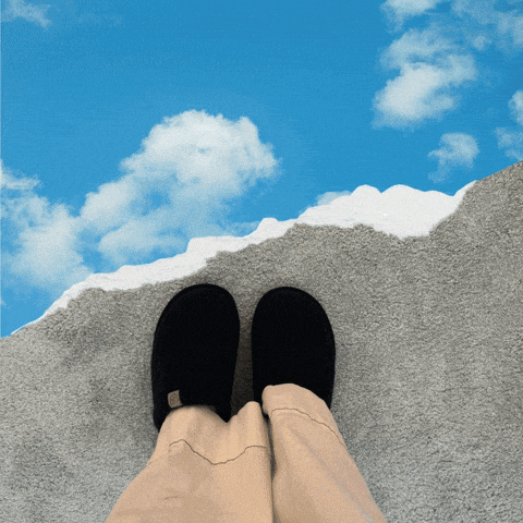 a person wearing black slippers is standing on a concrete surface with a blue sky behind them