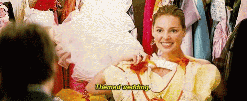 a woman in a wedding dress is talking on a cell phone while a man watches .