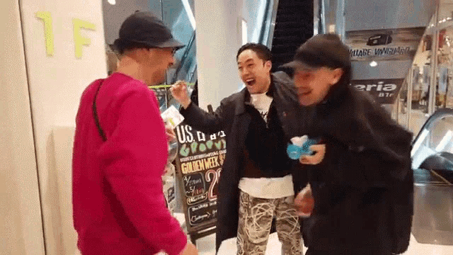 a group of men are standing in front of an escalator in a shopping mall .