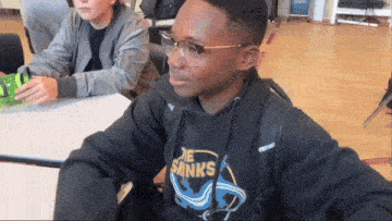 a boy wearing glasses and a black shirt that says the sinks