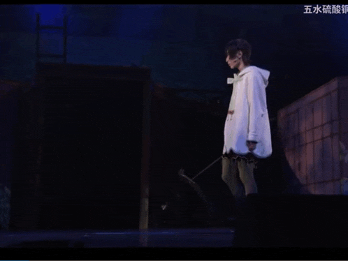 a woman in a white coat is standing on a stage with chinese writing on the bottom
