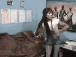 a woman is standing in front of a bed in a bedroom .